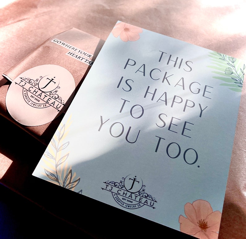 K&ouml;nnte beinhalten: Eine hellblaue Karte mit dem Text "This package is happy to see you too." Die Karte hat ein florales Design mit einem kleinen Logo unten, das "TJ Chateau Est 2008 A Crafted Jewelry Co." lautet.