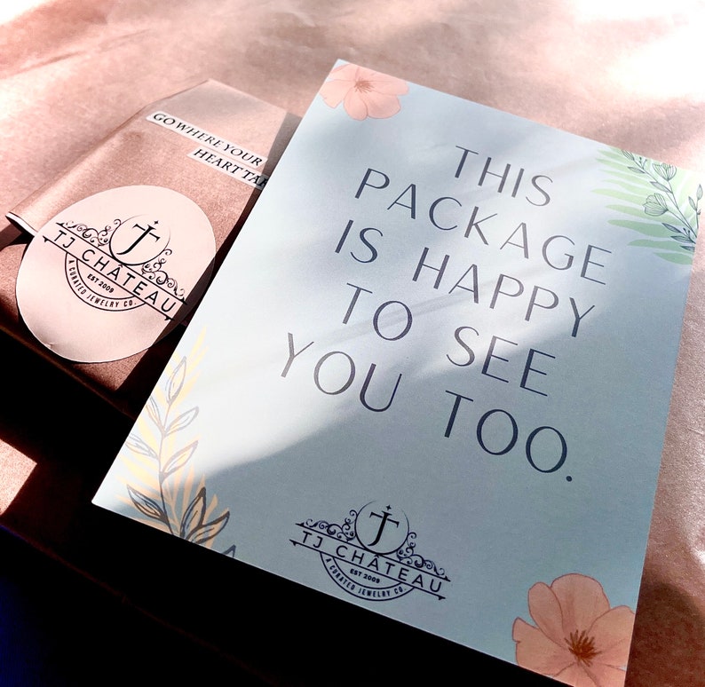 Pode incluir: Um cart&atilde;o retangular azul claro com o texto THIS PACKAGE IS HAPPY TO SEE YOU TOO, ilustra&ccedil;&otilde;es florais e o log&oacute;tipo TJ CHATEAU, colocado ao lado de um pacote castanho com um autocolante circular TJ CHATEAU e uma etiqueta GO WHERE YOUR HEART TAKES YOU.