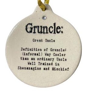 May include: Cream-colored ceramic ornament with the word "Gruncle" in black, along with a definition: "Way Cooler than an ordinary Uncle." The ornament has a gold ribbon for hanging and a small crystal.