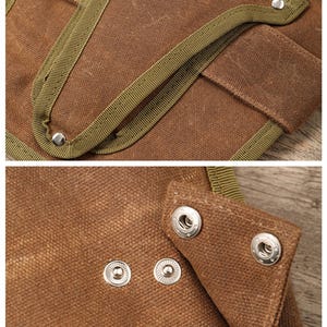 May include: Close-up of a brown canvas tool bag with olive green trim and silver snap closures. The bag has multiple pockets and reinforced stitching, suggesting durability and functionality for carrying tools.
