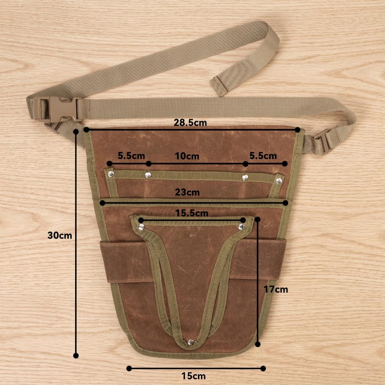 May include: A brown canvas tool belt with a beige adjustable strap and buckle. The belt has multiple pockets and is 11.8 inches tall, 5.9 inches wide, and 9 inches deep. The belt's strap is 11.2 inches long.