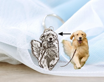 May include: A silver keychain featuring a black and white engraved image of a dog. The keychain is next to a photograph of a golden retriever.