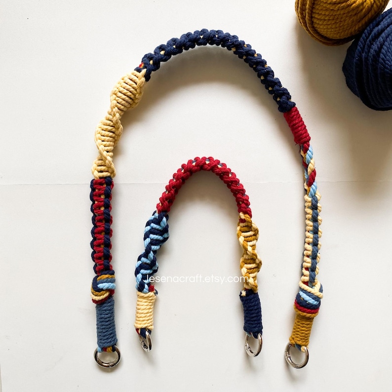 May include: Two macrame bag handles in navy, red, and tan. The larger handle has a spiral design and silver metal rings. The smaller handle has a similar design. The handles are on a white surface. The Etsy shop name is visible.