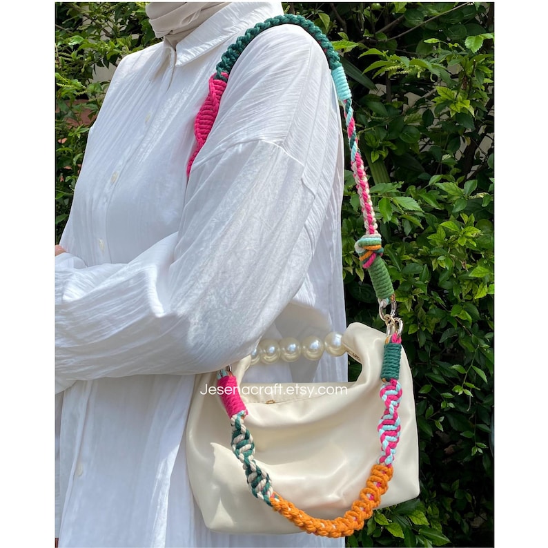 May include: A cream-coloured handbag with a pearl handle and a colourful braided strap. The strap features pink, green, orange, and blue sections. The bag has a rounded shape and a gold-coloured clasp. The text "Jesengcraft.etsy.com" is visible on the bag.
