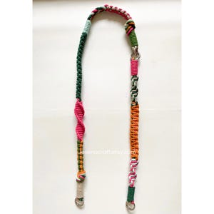 May include: A multi-coloured macrame strap featuring green, pink, orange, and cream sections. It has metal clasps at each end and a silver clasp in the middle. The Etsy shop name "Jesenacraft.etsy.com" is visible on the strap.