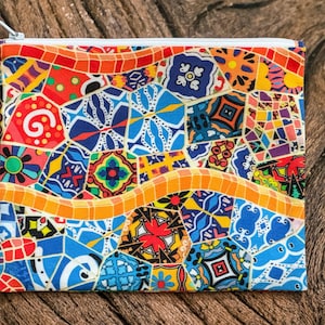 Op de afbeelding: Een kleurrijke rits-tas met een mozaïekpatroon in tinten blauw, rood, geel en groen. Het patroon lijkt op een betegelde vloer of muur.