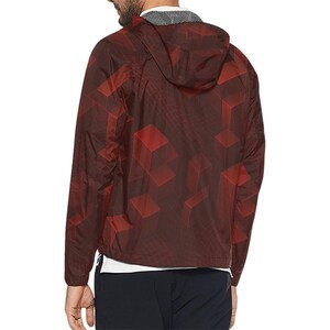 May include: Maroon hooded jacket with a geometric cube pattern in shades of red. The jacket has a full zipper, a hood, and long sleeves. The jacket is lightweight and appears to be made of a water-resistant material.