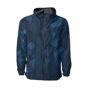 Puede incluir: Chaqueta cortavientos azul marino con un patrón geométrico de cubos en tonos azules. La chaqueta tiene cremallera completa, capucha y dos bolsillos laterales. El forro interior de la capucha es negro.