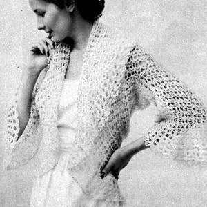 May include: A white crocheted shrug with a delicate openwork pattern. The shrug has a shawl collar and long sleeves with a slightly flared shape.