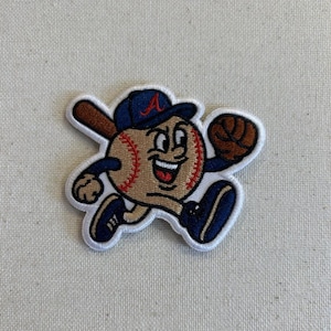 May include: Embroidered patch featuring a baseball character wearing a blue cap with a red "A" and holding a bat and glove. The baseball has a smiling face and is wearing blue shoes. The patch has a white border.