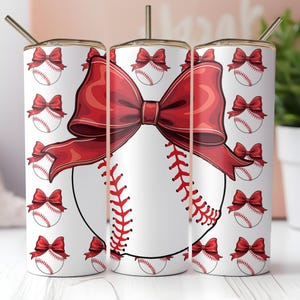May include: A white tumbler with a red bow and baseball design. The tumbler is decorated with a pattern of red bows and baseballs.