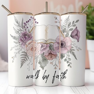 Puede incluir: Vaso blanco con un diseño floral con flores y follaje de acuarela moradas, rosas y verdes. El vaso tiene una tapa y una pajita doradas. Las palabras "walk by faith" están escritas en escritura negra en la parte delantera.
