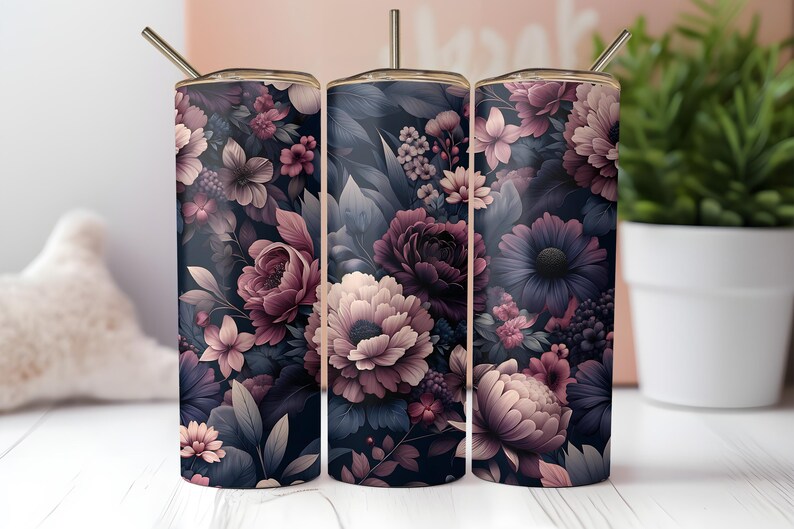 Puede incluir: Tres vasos de acero inoxidable con tem&aacute;tica floral con tapas y pajitas. Los vasos presentan un fondo azul marino oscuro con un patr&oacute;n de flores y hojas rosas, moradas y blancas. Los vasos son cil&iacute;ndricos y tienen un borde dorado met&aacute;lico.
