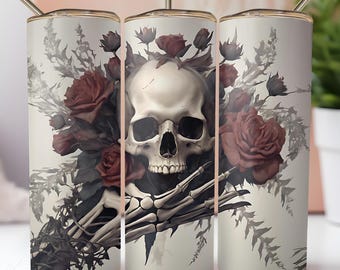 May include: A set of three stainless steel insulated tumblers with a skull and rose design. The design features a white skull surrounded by dark red roses and foliage, with a skeleton hand. Each tumbler has a gold-colored lid and straw.