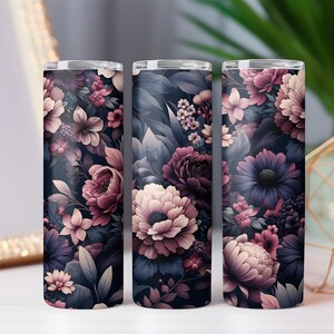 Puede incluir: Tres vasos cil&iacute;ndricos con un dise&ntilde;o floral. El patr&oacute;n presenta flores en tonos rosa, morado y crema sobre un fondo azul marino oscuro. Los vasos son probablemente de metal.