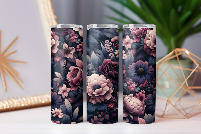 Puede incluir: Tres vasos cil&iacute;ndricos con un dise&ntilde;o floral. El patr&oacute;n presenta flores en tonos rosa, morado y crema sobre un fondo azul marino oscuro. Los vasos son probablemente de metal.