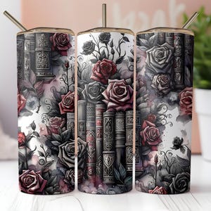 Op de afbeelding: Een roestvrijstalen beker met een bloemenontwerp met rode, grijze en zwarte rozen en een stapel boeken. De beker heeft een goudkleurig deksel en een rietje. Het ontwerp is op het oppervlak van de beker gedrukt.