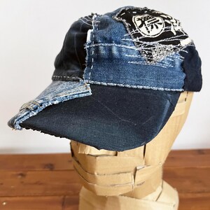 May include: A blue denim baseball cap with a patchwork design. The cap has a black brim and a white embroidered kanji character on the top.