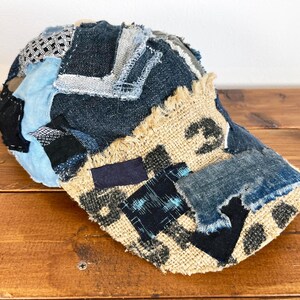 Op de afbeelding: Een blauwe en bruine patchwork baseballcap met rafelige randen. De cap is gemaakt van denim en jute stof.