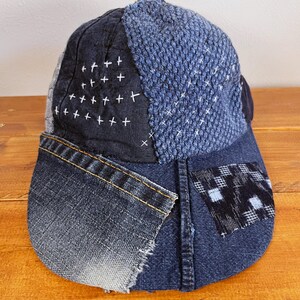 May include: A blue denim baseball cap with a patchwork design. The cap is made of different shades of blue denim and features a black and white checkered patch on the side.