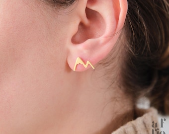 Puede incluir: Un par de pendientes de oro en forma de montaña. Los pendientes son pequeños y delicados, y son una excelente manera de agregar un toque de estilo a cualquier atuendo.