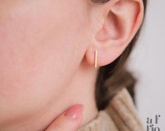 May include: A pair of gold bar stud earrings. The earrings are simple and minimalist, and they are perfect for everyday wear.