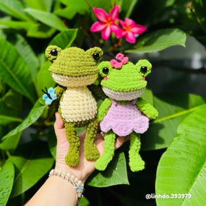 Customer made crochet frog couple amigurumi photographed outdoors with tropical flowers, bright green chenille yarn, made from Lilypond Froggies crochet pattern PDF