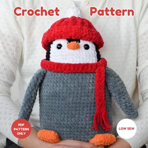May include: A crocheted penguin wearing a red hat, scarf, and orange feet. The penguin has a white belly, black eyes, and an orange beak. The text "Crochet Pattern" is at the top. The text "PDF Pattern Only" and "Low Sew" are also visible.