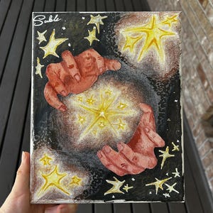 May include: A painting on canvas with a black background and two red hands holding a glowing yellow star. The star is surrounded by smaller yellow stars. The painting is signed "Sable" in the top left corner.