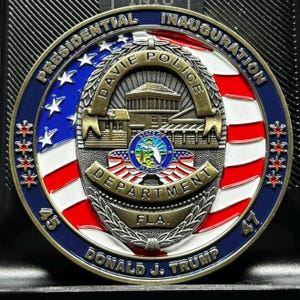 May include: A gold-colored commemorative coin with a blue, red, and white American flag design. The coin features the text "PRESIDENTIAL INAUGURATION" and "DAVIE POLICE DEPARTMENT FLA."  The coin also features the text "DONALD J. TRUMP" and the numbers "45" and "47".
