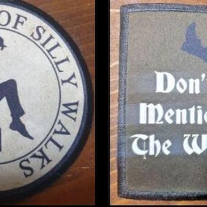 May include: Two fabric patches. The first patch is round and features a black and white illustration of a man walking with a briefcase. The text around the illustration reads "The Ministry of Silly Walks". The second patch is rectangular and features a black and white illustration of a man kicking his leg up in the air. The text on the patch reads "Don't Mention The War!"