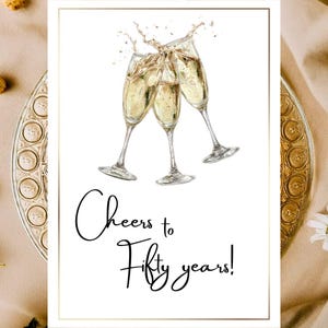 Könnte beinhalten: Eine Grußkarte mit goldenem Rand zeigt drei Sektgläser, die anstoßen, mit spritzenden Blasen. Der Text "Cheers to Fifty years!" ist in eleganter Schrift geschrieben. Die Karte befindet sich auf einem beigen Hintergrund.