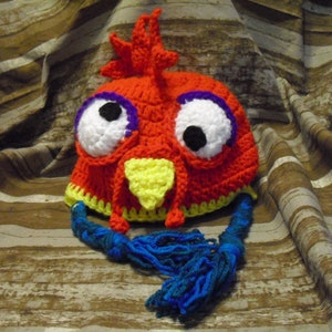 May include: A red, yellow, white, purple, and blue crocheted parrot hat with large googly eyes and a long tail.