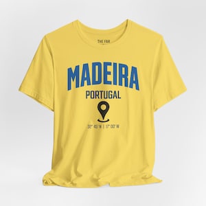 May include: A bright yellow short-sleeve t-shirt featuring the blue text MADEIRA, the word PORTUGAL, a black map location pin icon, and the coordinates 32 45' N | 17 00' W printed in black. The inner collar label displays the text THE FAR.