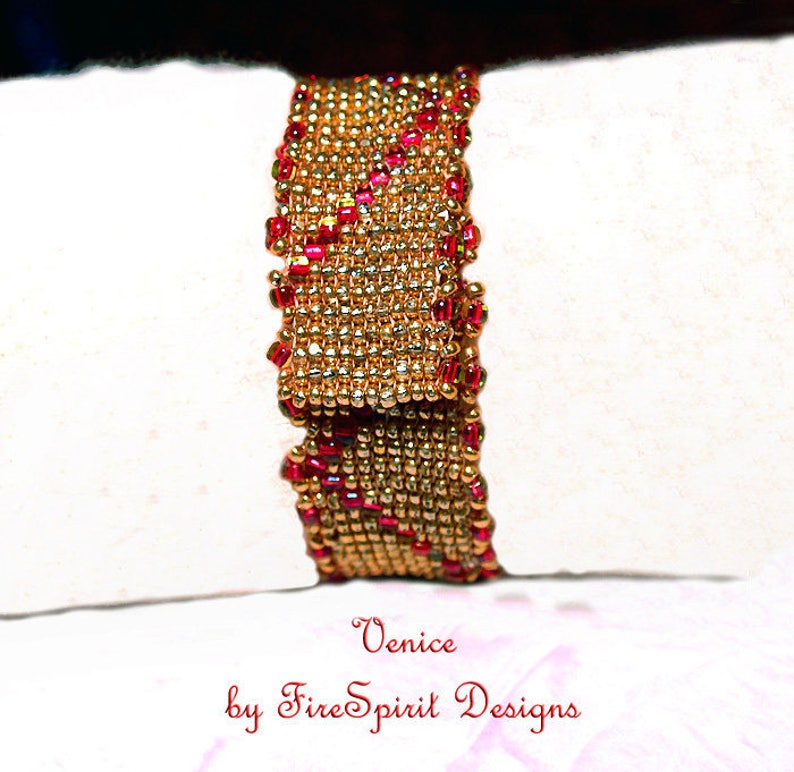Pode incluir: Um bracelete de contas douradas e vermelhas com um design tecido. O bracelete &eacute; etiquetado como "Venice by FireSpirit Designs".