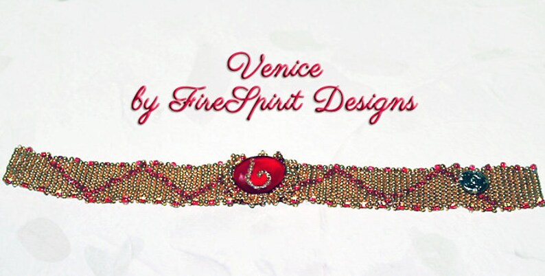 Pode incluir: Um bracelete de contas douradas e vermelhas com um caboch&atilde;o vermelho no centro. O bracelete est&aacute; etiquetado como "Venice by Fire Spirit Designs".