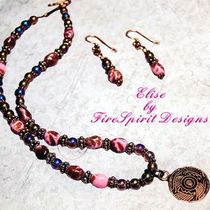 May include: A pink and brown glass bead necklace with a copper pendant featuring a floral design. The necklace is paired with matching earrings. The text "Elise by Fire Spirit Designs" is visible in the image.