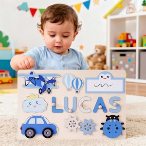 May include: Wooden name puzzle featuring the name "LUCAS" in blue letters. The puzzle includes airplane, car, cloud, and ladybug shapes. The background is a light wood colour.