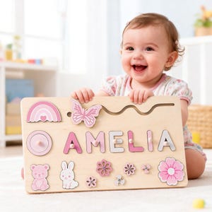 May include: Wooden puzzle board with the name "AMELIA" in pink letters. The board features a rainbow, butterfly, flowers, bear, and bunny. A developmental toy for young children.
