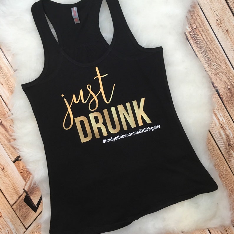 May include: Black tank top with gold lettering that says "just drunk" and the hashtag "#bridgettebecomesBRIDEgette".