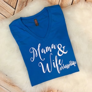 Puede incluir: Una camiseta azul real de cuello en V con el texto "Mama & Wife #blessedlife" en blanco.