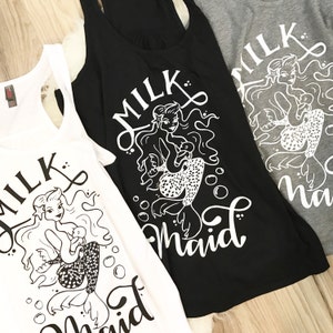 May include: Three tank tops with a mermaid graphic and the text "Milk Maid". The tank tops are white, black, and gray.