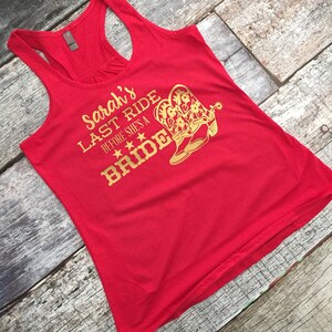 May include: Red tank top with gold text that reads "Sarah's Last Ride Before She's a Bride" with a pair of gold cowboy boots.