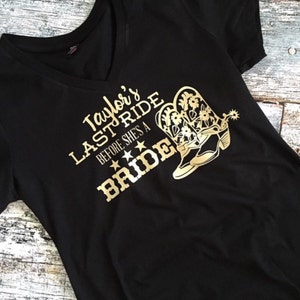 K&ouml;nnte beinhalten: Schwarzes T-Shirt mit goldener Aufschrift "Taylor's Last Ride Before She's A Bride" und einem Paar goldenen Cowboystiefeln.