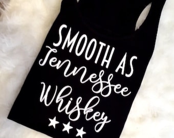 May include: Black tank top with white text that reads "Smooth as Tennessee Whiskey" with three white stars below the text.