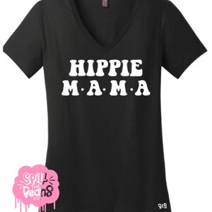 Puede incluir: Camiseta negra de cuello en V con texto blanco que dice "HIPPIE MAMA" en una fuente retro.