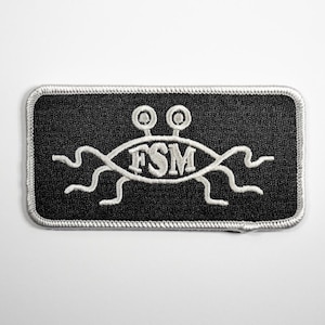 May include: A black and white embroidered patch with a stylized image of a flying spaghetti monster. The monster has two eyes, a long body, and the letters "FSM" written on its body.