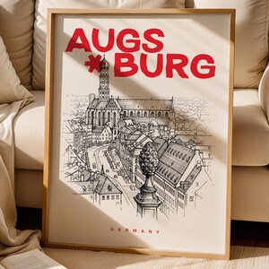 Könnte beinhalten: Ein gerahmter Druck mit einer Schwarz-Weiß-Illustration von Augsburg, Deutschland, und dem Namen der Stadt in Rot. Der Druck zeigt eine detaillierte Stadtlandschaft und das Wort „GERMANY“ in Rot.