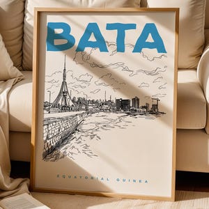 May include: A framed art print featuring a black and white illustration of a cityscape with the word "BATA" in blue at the top. The text "EQUATORIAL GUINEA" is at the bottom. The artwork is in a light wood frame.