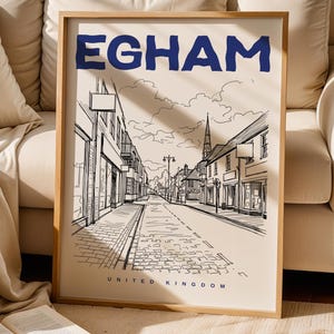Könnte beinhalten: Ein gerahmter Kunstdruck mit einer Schwarz-Weiß-Skizze einer Straßenszene in Egham, Vereinigtes Königreich. Das Wort "EGHAM" ist oben in Blau gedruckt. Die Worte "UNITED KINGDOM" sind unten gedruckt.